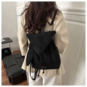 Detail of matte black drawstring backpack with triangular flap and Fashion lettering