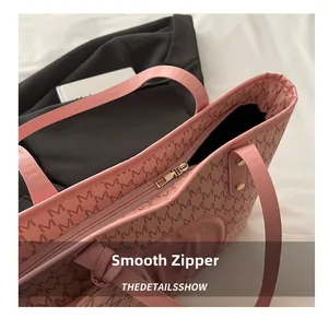 Detailaufnahme des glatten goldenen Reißverschlusses und der rosa Tragetasche mit M-Muster