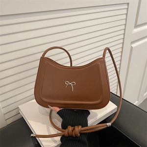Minimalist brown crescent shoulder bag with silver bow detail on white backdrop