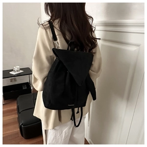 Close-up of black lightweight nylon backpack featuring drawstring closure and flap design