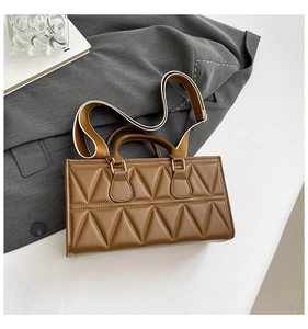 Close-up of geometric triangle quilting texture on the brown leather crossbody bag
