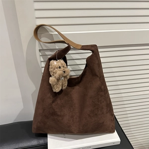 Brown suede hobo shoulder bag with a cute plush dog charm and wide leather strap