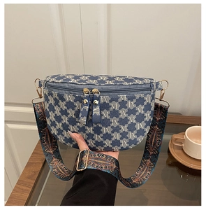 Detailansicht der blauen Monogramm-Gürteltasche mit besticktem Gurt und Goldbeschlägen