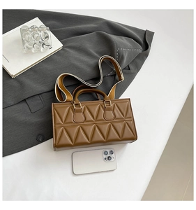 Macro view of brown quilted handbag with triangle stitching and wide shoulder strap
