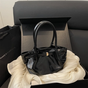 Chic black patent leather bucket bag with gold buckle on a premium silk gift box
