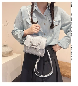 Detail of silver metallic mini bag with bow clasp decoration and adjustable shoulder strap