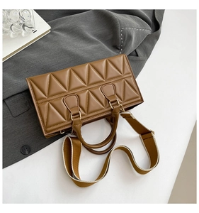 Detail of brown quilted bag with triangle pattern, dual handles and wide shoulder strap