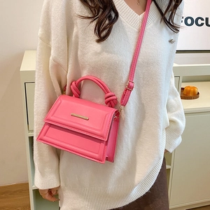 Pink PU leather crossbody bag with a knot handle and gold metal trim shown on a model