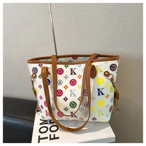 Detail of colorful geometric floral prints and brown leather handles on a tote bag