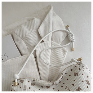 Detail view of white corduroy tote bag showing metal strap tips and brown heart prints