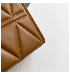 Detailed close-up of V-shaped quilted stitching on caramel brown leather crossbody bag