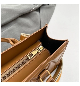 Detailed top view of brown quilted handbag featuring a secure gold metal zipper closure