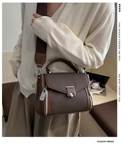 Brown crossbody bag with wide canvas strap and silver zipper detail shown on model