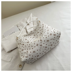 Detail of white corduroy tote bag featuring brown bow prints and soft rope handles