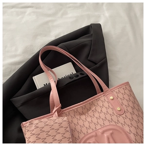 Detail view of pink leather tote bag with all-over M pattern and matching pouch insert