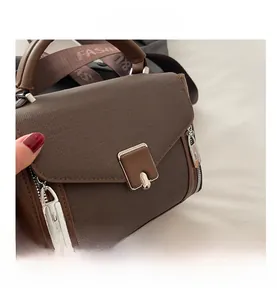 Detail of dark brown canvas and leather bag with square metal lock and fashion strap