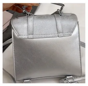 Detailed macro view of the silver metallic textured fabric and flap on this mini square bag