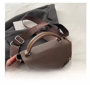 Detail of brown leather bag featuring grid texture and wide fashion shoulder strap