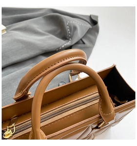 Close-up of metal zipper and quilted stitching detail on brown faux leather handbag