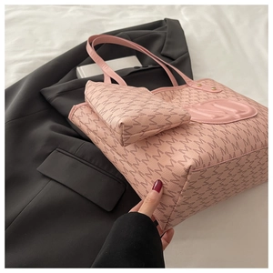 Detail view of pink tote bag with letter M monogram pattern and round embossed emblem