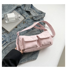 Detail of light pink nylon crossbody bag with dual utility pockets and adjustable strap