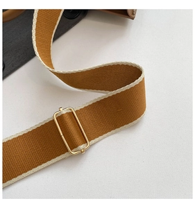 Detail of adjustable woven bag strap with golden metal buckle and stitching