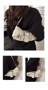 Détail du sac beige avec boucles argentées et texture plissée sur pull noir