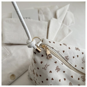 Close-up of cream corduroy fabric with butterfly prints and golden zipper detail