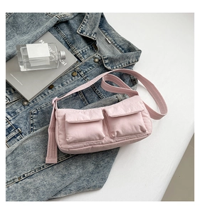 Detail of pink crinkled nylon crossbody bag with dual pockets on denim background