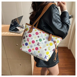 Détail d'un sac cabas blanc avec imprimé monogramme coloré et anses en cuir marron