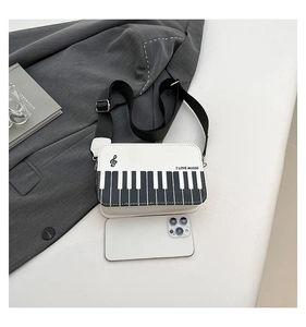 Detailed view of creative piano-themed crossbody bag with mobile phone for size scale