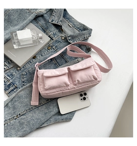 Detailed view of light pink nylon shoulder bag with double pockets on blue denim
