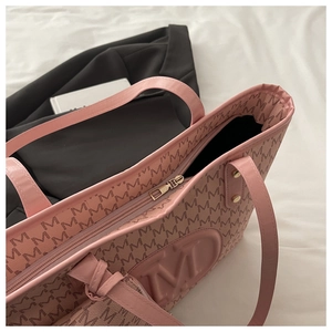Detail of pink faux leather tote bag with M-pattern print and embossed logo design