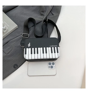 Detail of creative piano keyboard crossbody bag with I LOVE MUSIC text and phone for scale