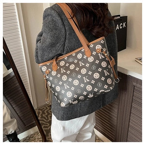Détail du cabas gris monogrammé avec bandoulières en cuir marron et anneaux dorés