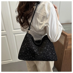 Detail of black corduroy hobo bag with small heart patterns and knotted strap detail