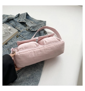 Detail of pink nylon crossbody bag featuring double front pockets and metal snap buttons