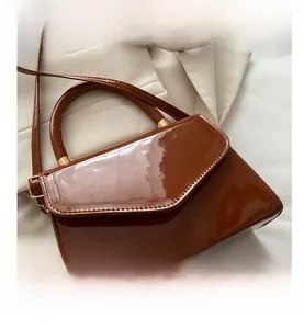 Detailed close-up of brown patent leather handbag with glossy finish and gold hardware
