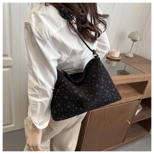 Detail of black bow hobo bag featuring heart patterns and fashionable knotted shoulder strap