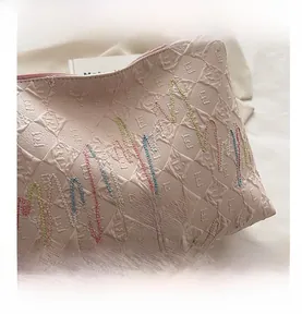 Close-up of pink canvas tote bag with quilted pattern and colorful wavy embroidery detail