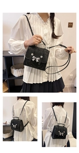 Detail of black mini square bag with silver metal bow and dual backpack-crossbody straps