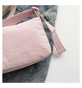 Close-up of pink nylon crossbody bag showing crinkle texture and wide shoulder strap
