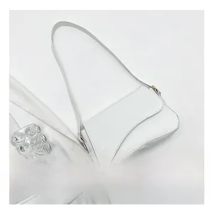 Detail of white crocodile embossed leather handbag with curved base and gold hardware