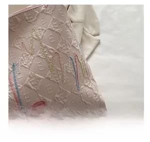 Close-up of pink quilted tote bag fabric with colorful embroidery and leather label