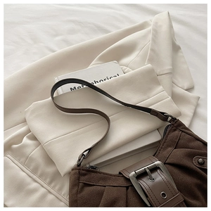 Détail du sac bandoulière en daim marron foncé avec design plissé et boucle en métal
