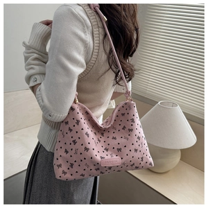 Detail of pink corduroy tote bag with bow patterns and fashion label on shoulder strap