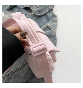 Detail of light pink quilted crossbody bag showing soft texture and wide shoulder strap