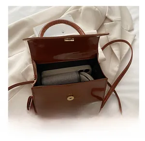 Internal view of the brown patent leather handbag showing capacity and magnetic clasp