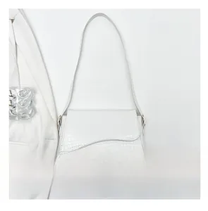White crocodile pattern shoulder bag size comparison with a mobile phone on a white suit