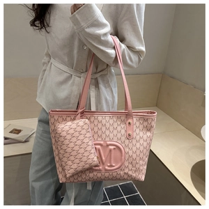 Close-up of pink tote bag with M-pattern print, gold rivets, and matching coin purse